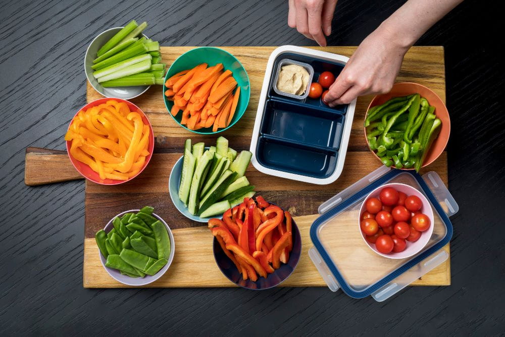 Healthy lunch box with cut vegetables being prepared for kids.