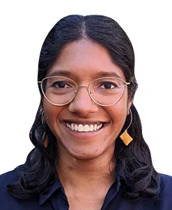 Headshot of Dheepa Jeyapalan, she is wearing a navy top, orange earrings and silver rimmed glasses.