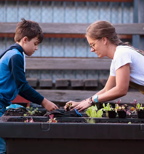 A young boy and a woman gardening with raised beds.