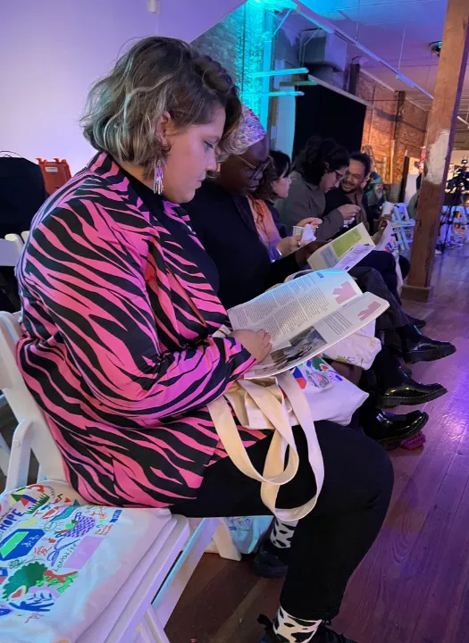 A photo of a person at the Future Reset launch event, reading a program booklet.