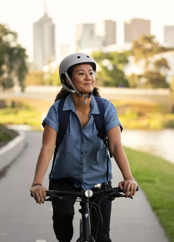 Woman cycling by the river with the Melbourne cityscape in the background