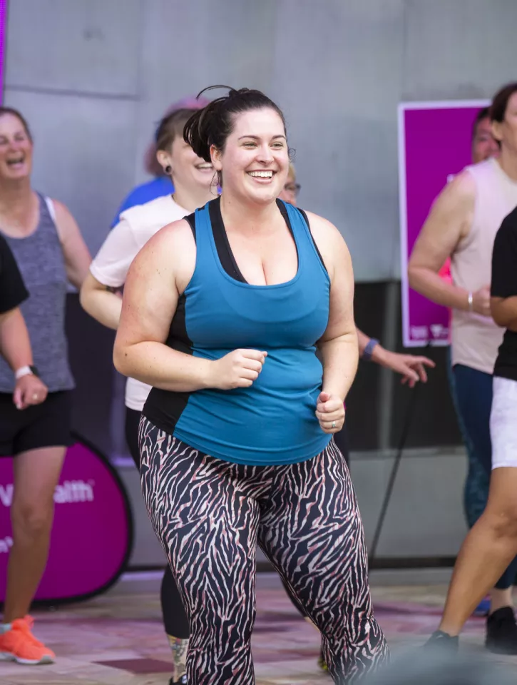 A group of women wearing activewear, dancing and smiling