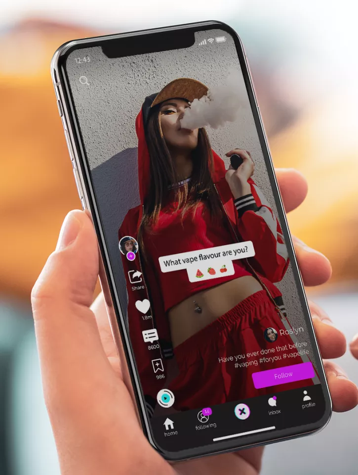 A photo of hands holding a phone. The phone screen shows an image of a person vaping on social media, looking glamorous.
