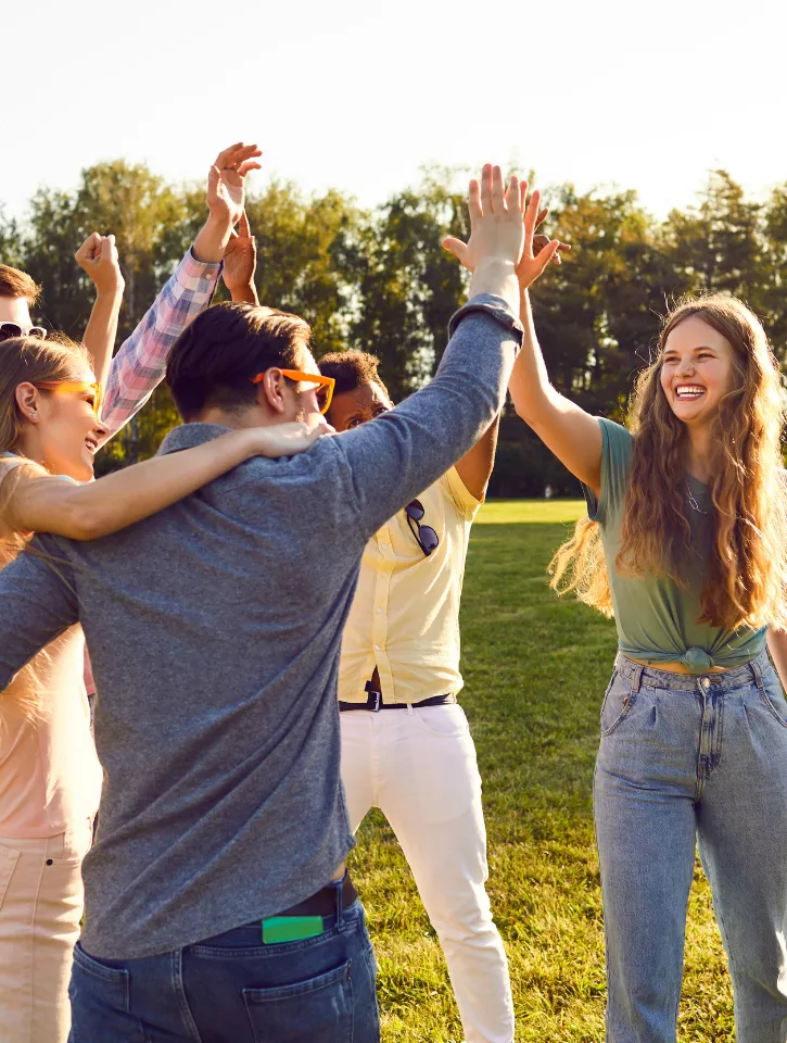 A photo of happy people in a park high-fiving