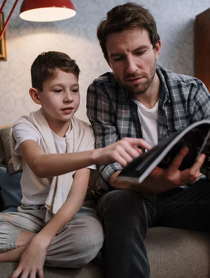 A photo of a father and son looking at a book together